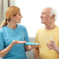 Caretaker giving medication to an elderly man