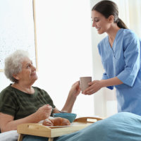 Caretaker giving water to an elderly woman