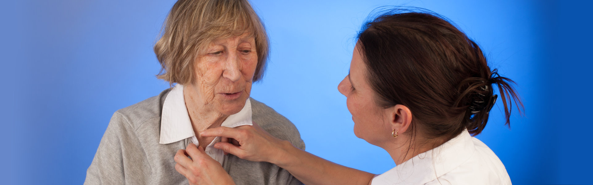 Caretaker dressing an elderly woman